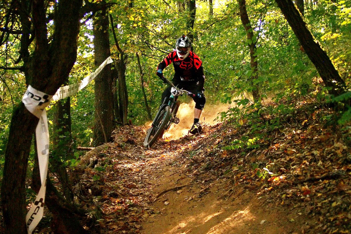 Biciclist pe potecă de munte în zona împădurită a Reșiței